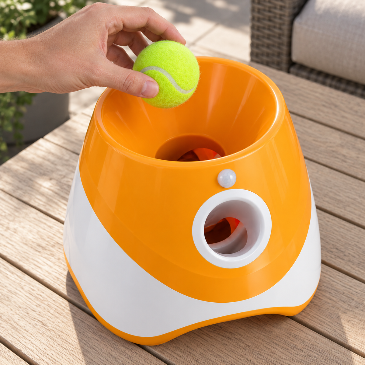 Ein Mini-Tennisball wird von oben in die Einfüllmulde des Ballwerfers gegeben