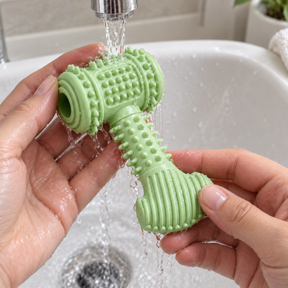 Grünes Tatzenkau Spielzeug wird von Hand mit Wasser abgespült